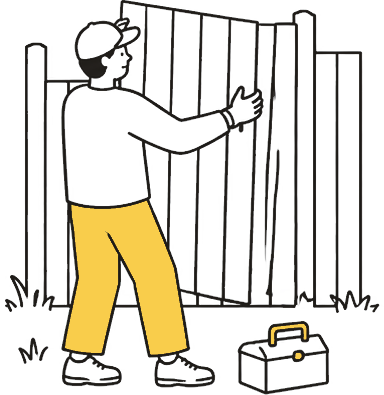 A person fitting a wooden fence panel in a back yard